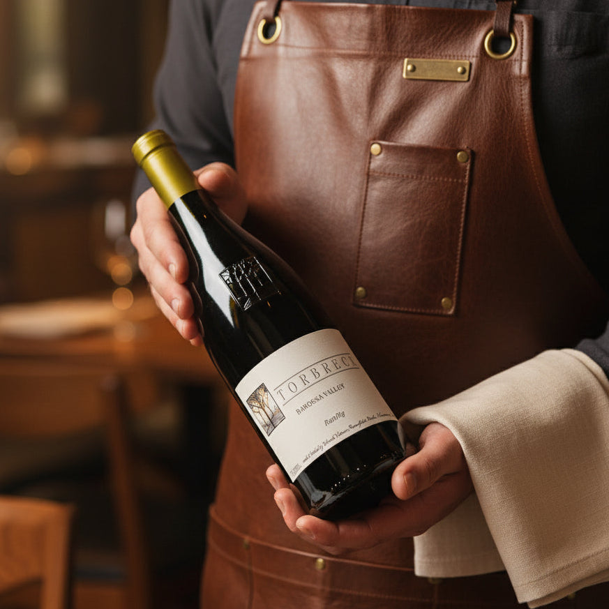 Load image into Gallery viewer, Person holding a bottle of Torbreck_RunRig_Shiraz wine in a restaurant setting