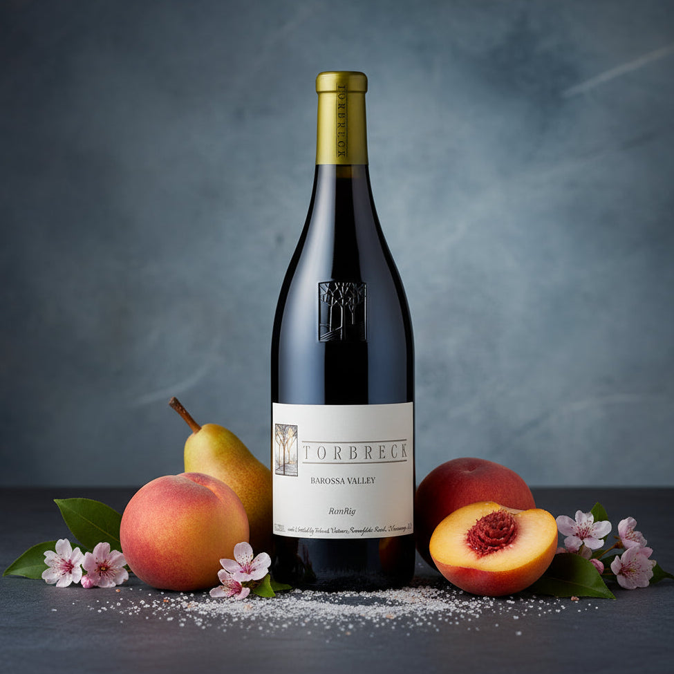 Load image into Gallery viewer, Torbreck_RunRig_Shiraz wine bottle surrounded by fruits and flowers on a dark surface.