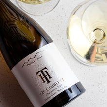 Load image into Gallery viewer, Bottle of Trinity Hill wine with a glass of white wine on a textured surface