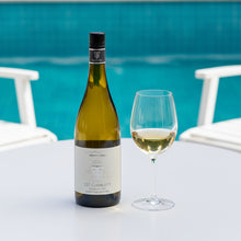 Load image into Gallery viewer, A bottle of Trinity Hill 125 Chardonnay wine next to a half full wine glass with a pool in the background