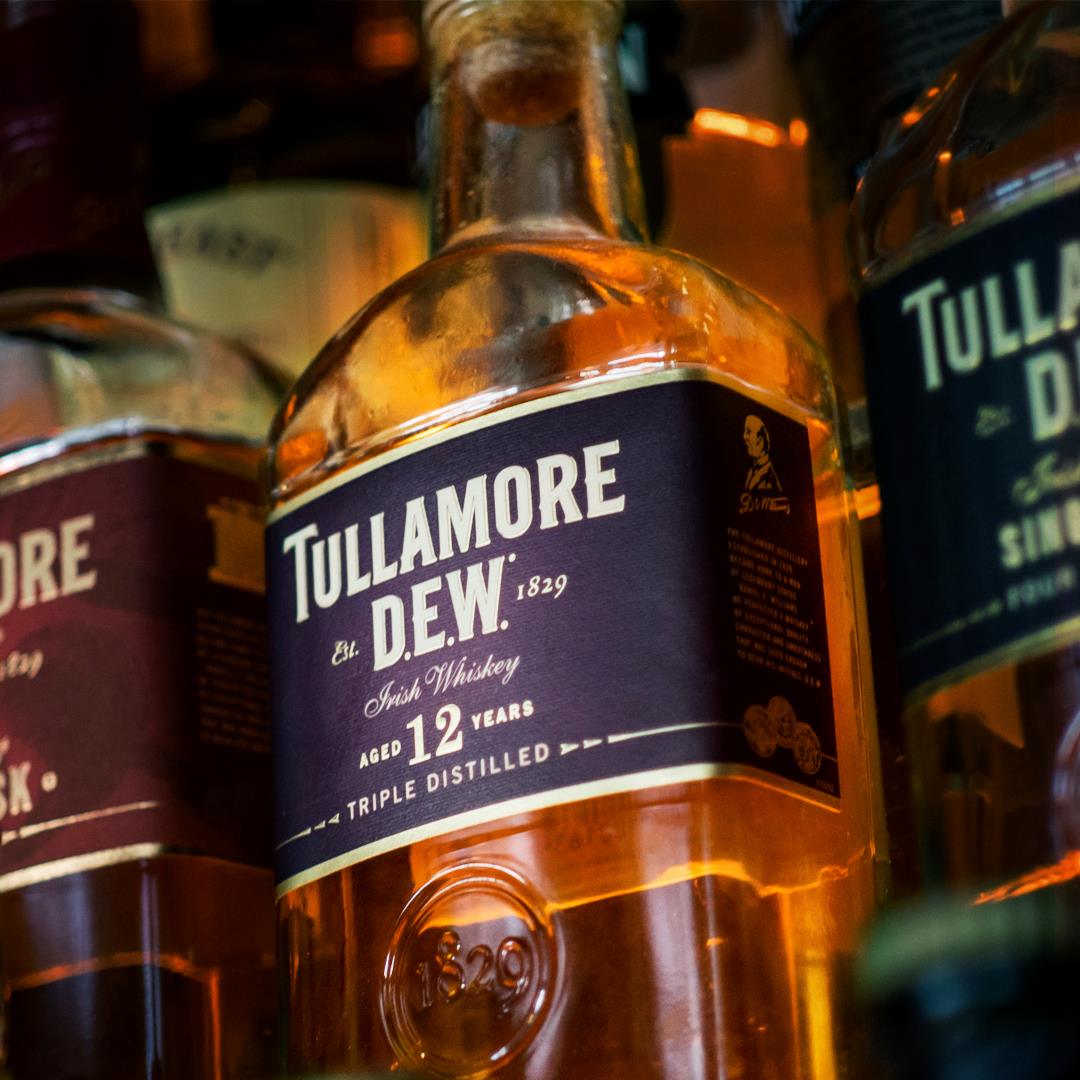 Load image into Gallery viewer, Close-up of Tullamore D.E.W. whiskey bottles on a shelf.