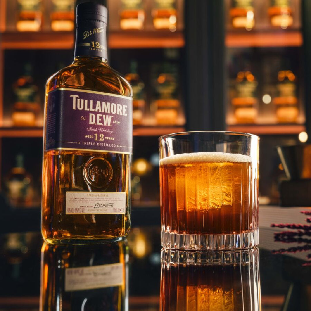Load image into Gallery viewer, Bottle of Tullamore Dew whiskey and a glass of whiskey on a bar counter.