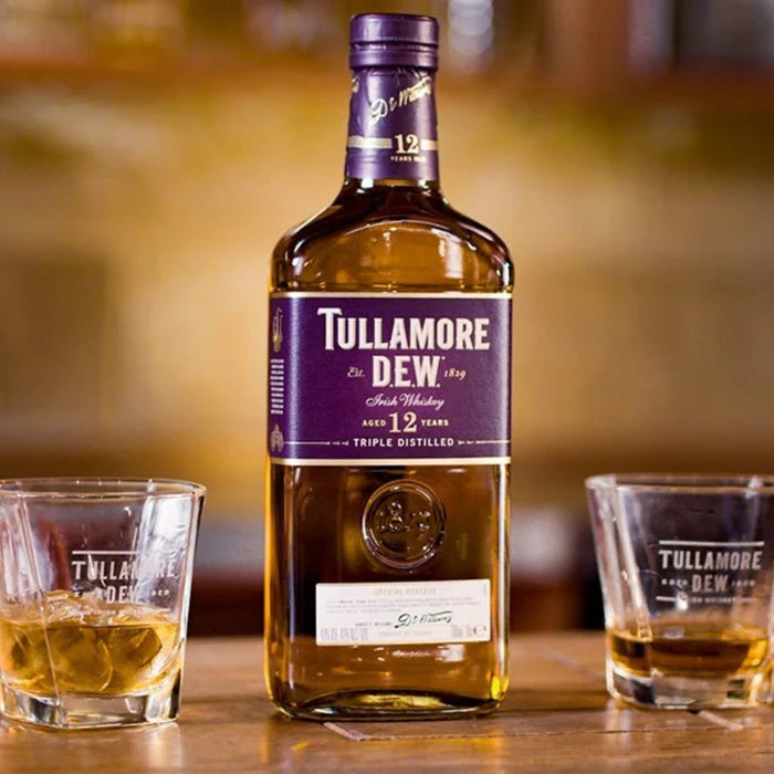 Load image into Gallery viewer, Bottle of Tullamore Dew whiskey with two glasses on a wooden surface.