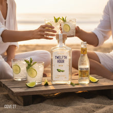 Load image into Gallery viewer, Two people enjoying cocktails with Twelfth Hour gin and Fever-Tree tonic on a beach.