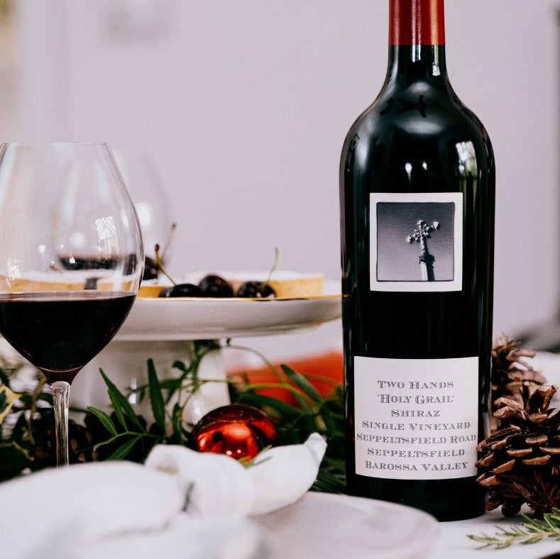 Load image into Gallery viewer, Two Hands Holy Grail Shiraz Seppeltsfield Road red wine bottle with a glass on a festive table setting
