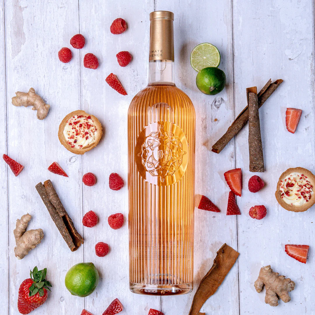 Load image into Gallery viewer, Bottle of rosé on a wooden surface with fruits and spices around