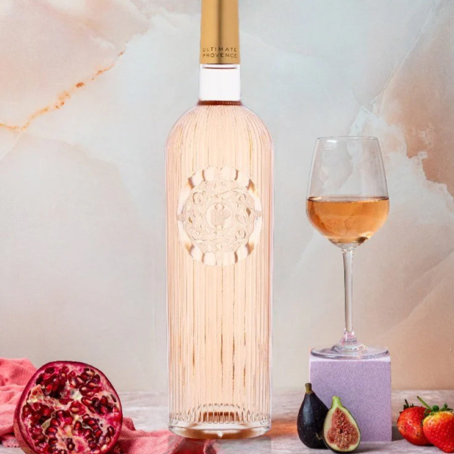 Load image into Gallery viewer, Bottle of rose wine with a glass, pomegranate, figs, and strawberries on a marble surface.