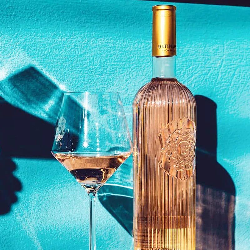 Load image into Gallery viewer, A bottle of Ultimate Provence Rosé and a glass of wine with a teal background