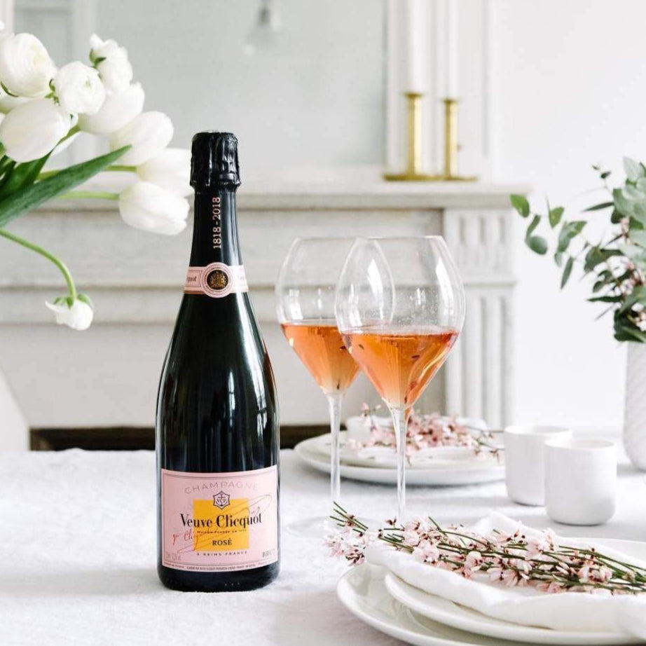 Load image into Gallery viewer, Bottle of Veuve Clicquot ROSÉ champagne with two glasses of pink champagne on a table set for a meal.