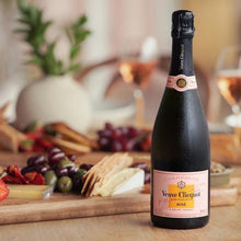 Load image into Gallery viewer, Bottle of Veuve Clicquot Rosé champagne on a table with a charcuterie board in the background