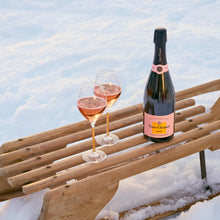 Load image into Gallery viewer, Bottle of Veuve Clicquot champagne and two glasses on a wooden bench in the snow.