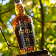 Load image into Gallery viewer, Weller 12 whiskey bottle against a natural background with greenery