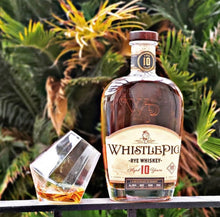 Load image into Gallery viewer, WhistlePig Rye Whiskey bottle with a glass of whiskey on a surface with plants in the background