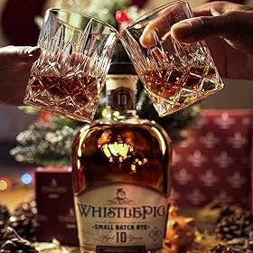 WhistlePig Small Batch Rye bottle with two people making a toast with their glasses of whiskey on a christmas background
