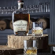 Load image into Gallery viewer, WhistlePig Small Batch Rye bottle standing on a piece of wood with a glass of whiskey and ice