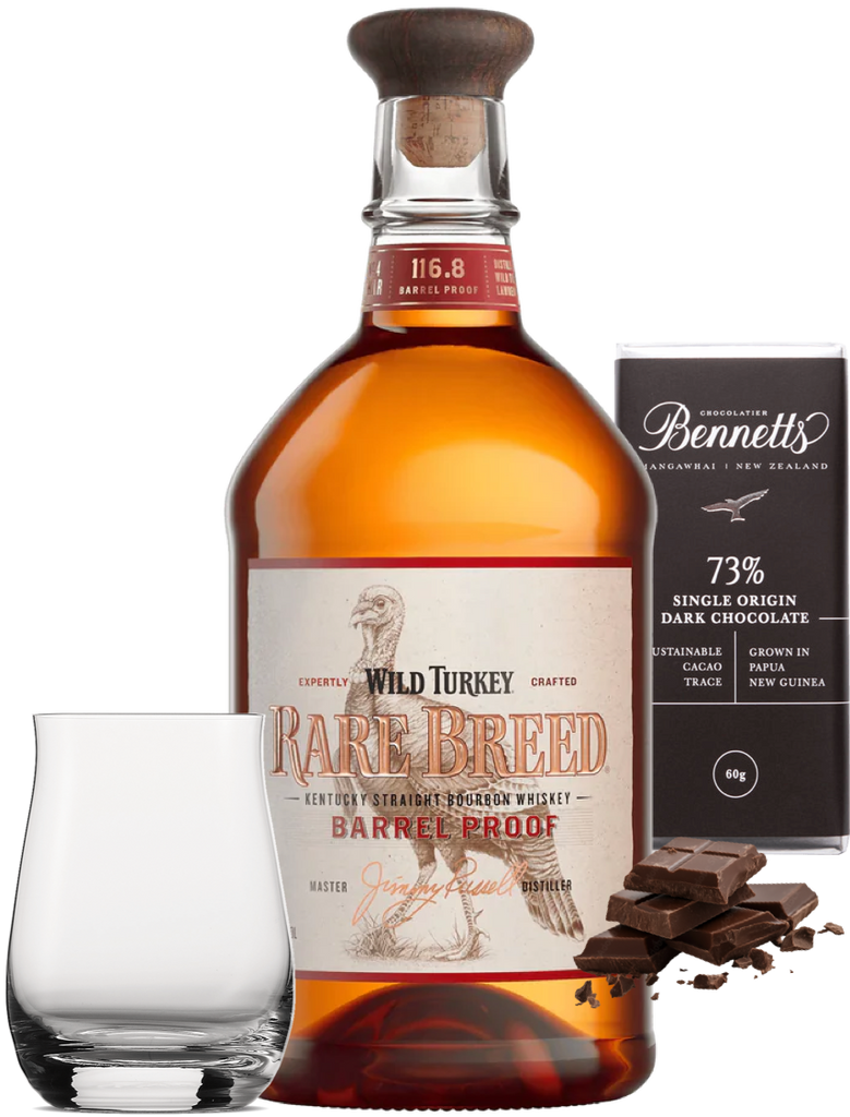 Bottle of Wild Turkey Rare Breed whiskey with a glass, chocolate, and Bennett's chocolate packaging on a white background