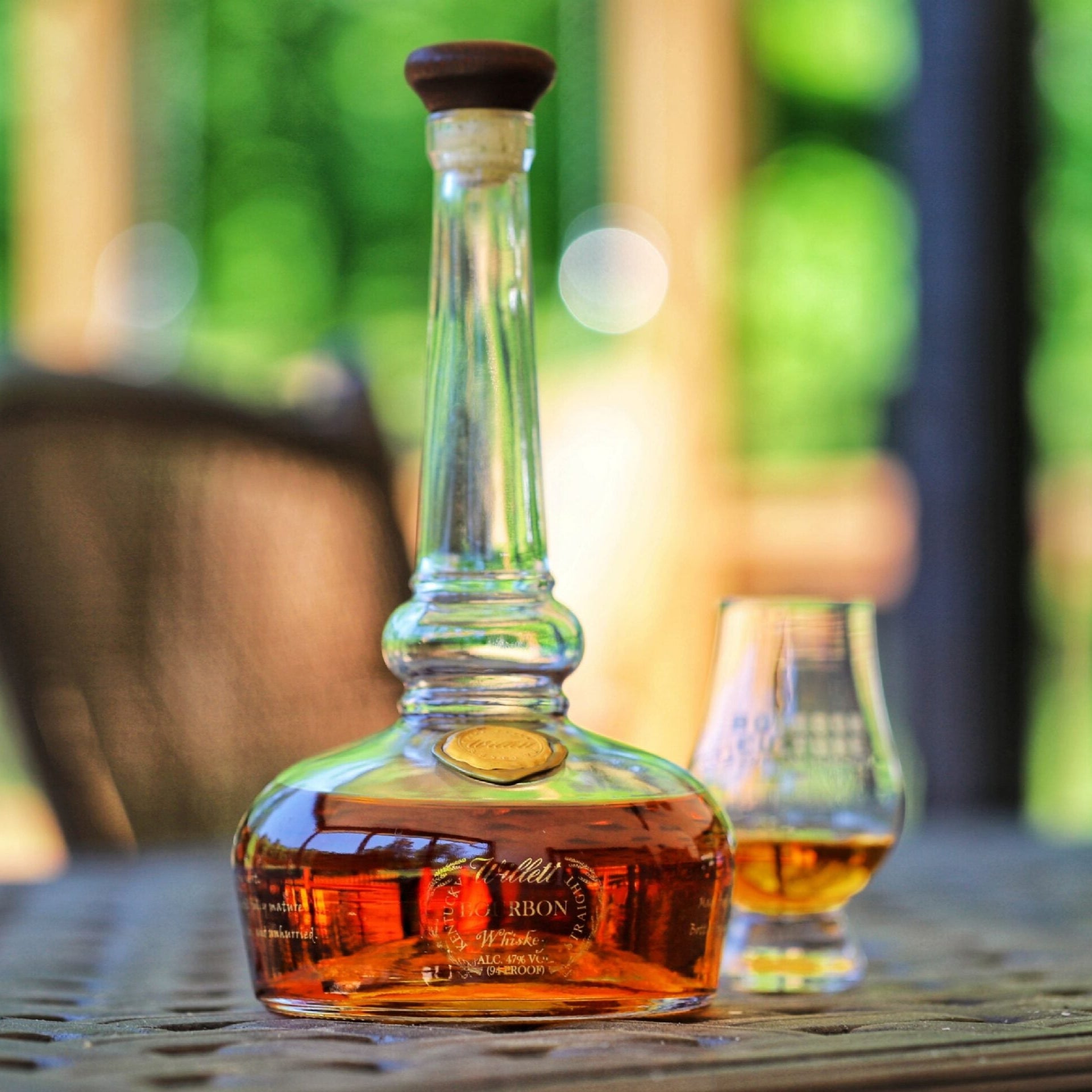 Load image into Gallery viewer, Bottle of liquor on a table with a blurred outdoor background