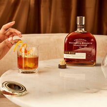 Load image into Gallery viewer, A bottle of an open bourbon and a cocktail on a marble table.