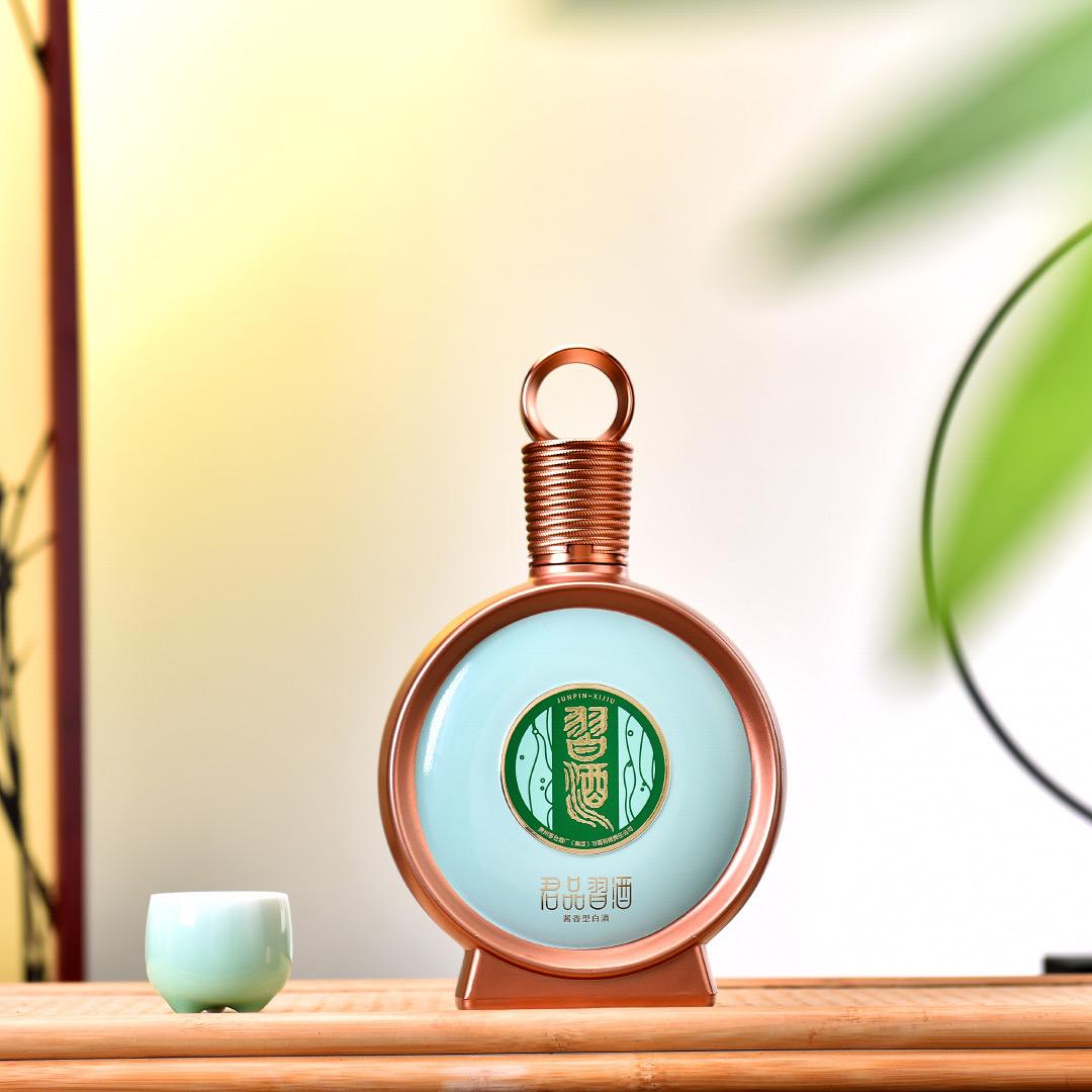 Load image into Gallery viewer, A bottle of Xijiu JunPin Baijiu 53% 500ml  next to a small sipping cup