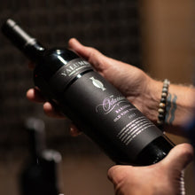 Load image into Gallery viewer, Person holding a Yalumba Rare and Fine The Octavius shiraz red wine bottle with visible branding in a blurred indoor setting
