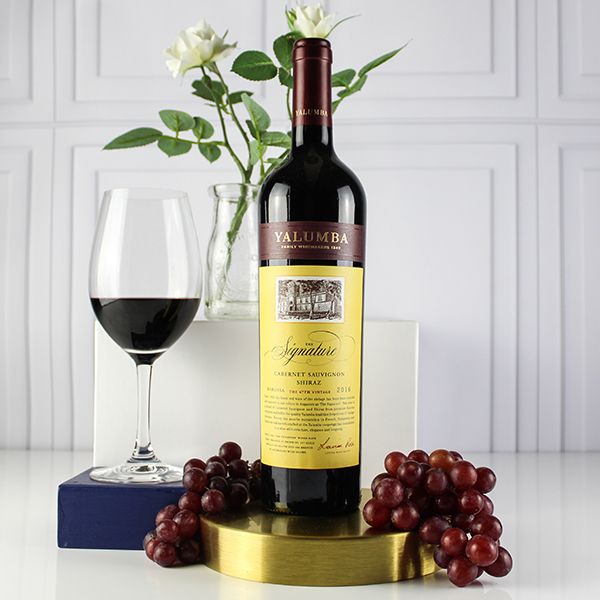 Load image into Gallery viewer, Yalumba The Signature Cabernet Shiraz wine bottle with a glass of red wine and grapes on a white surface.
