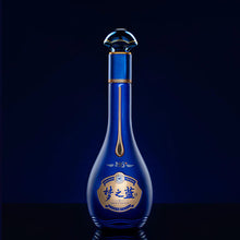 Load image into Gallery viewer, Blue bottle with gold accents on a black background