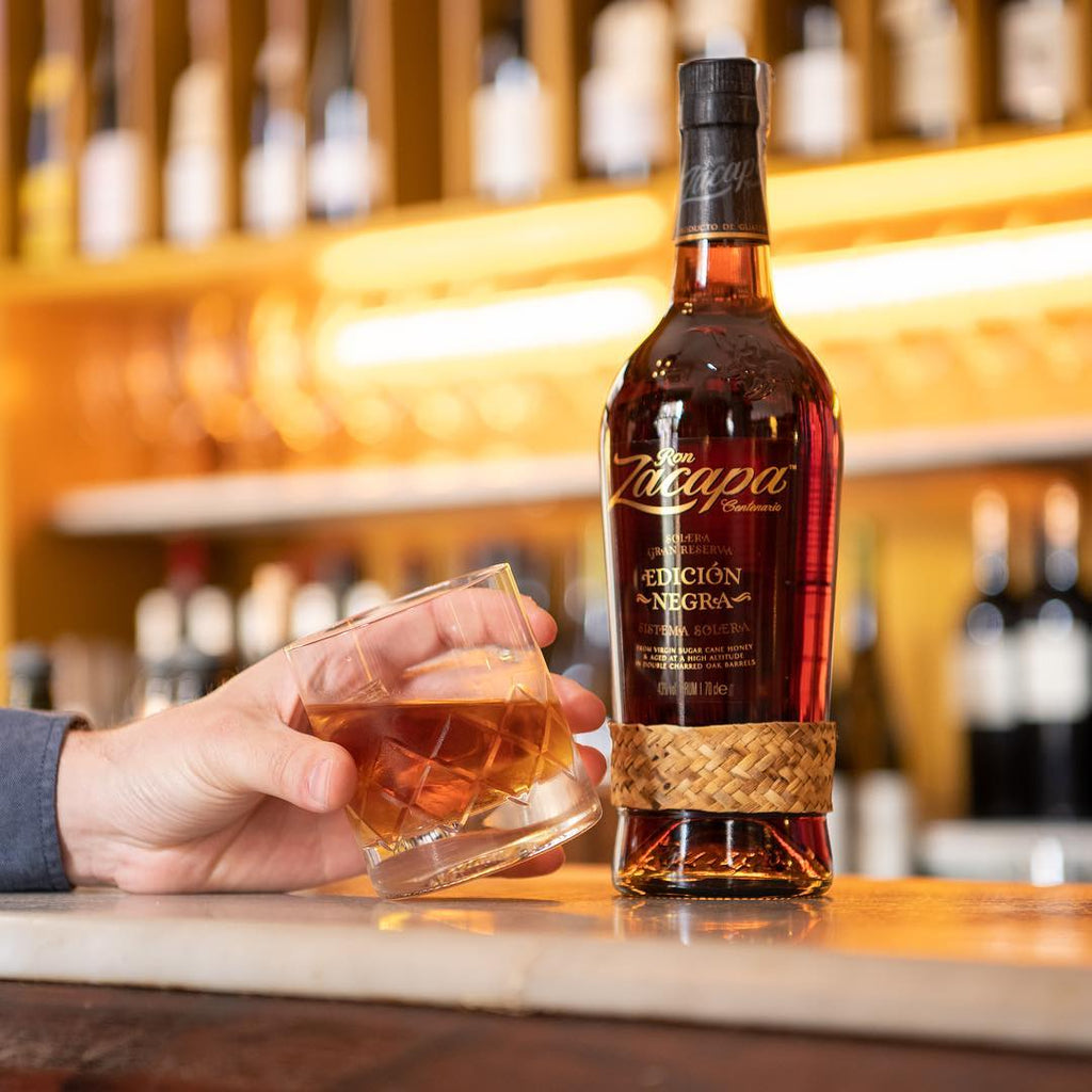 Bottle of Zacapa Edicion Rum with a glass of rum on a bar counter