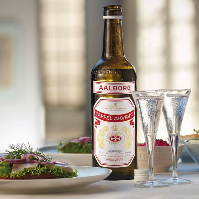 Aalborg beer bottle with glasses and snacks on a table