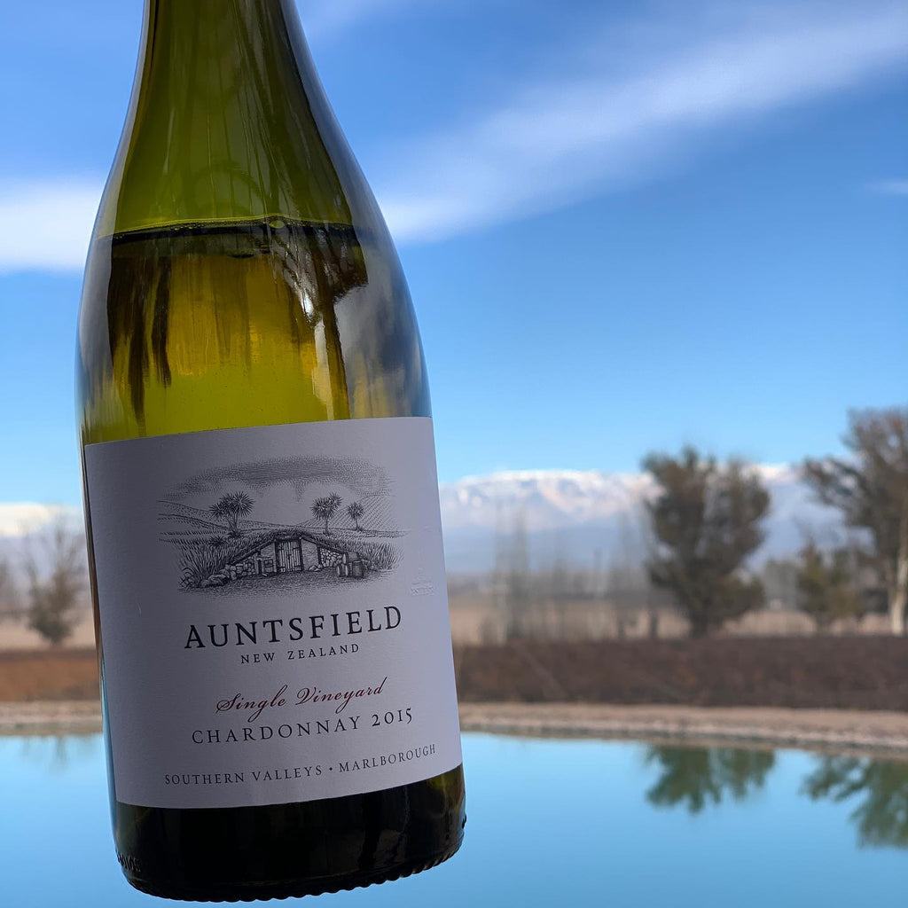 Auntsfield Chardonnay wine bottle with a scenic background