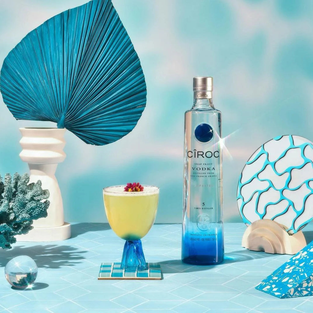 Ciroc vodka bottle with a cocktail and decorative elements on a blue background