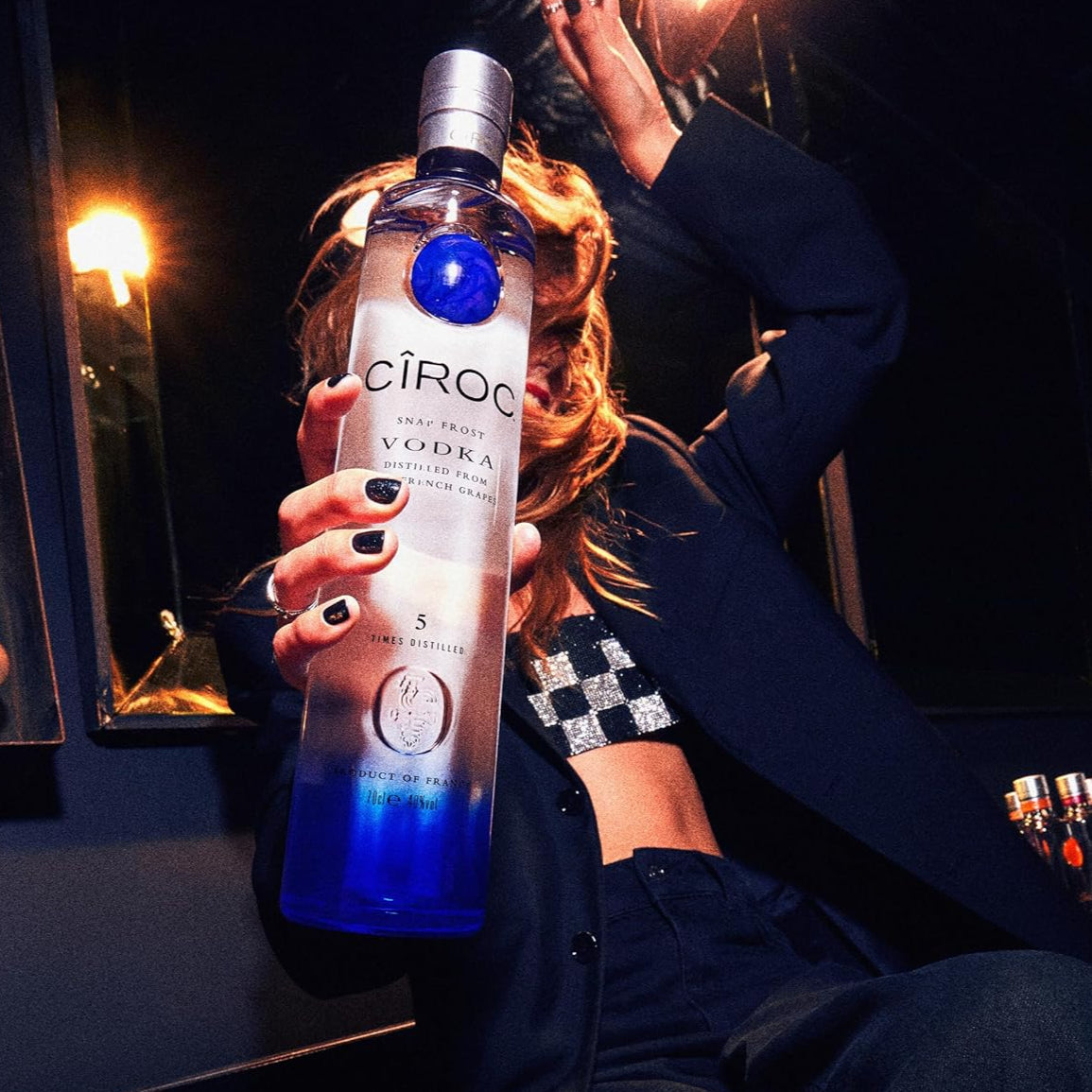 Load image into Gallery viewer, Woman holding a bottle of Ciroc Vodka in a dimly lit setting