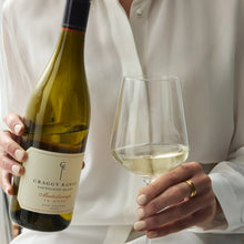 Load image into Gallery viewer, Person holding a bottle and glass of white wine