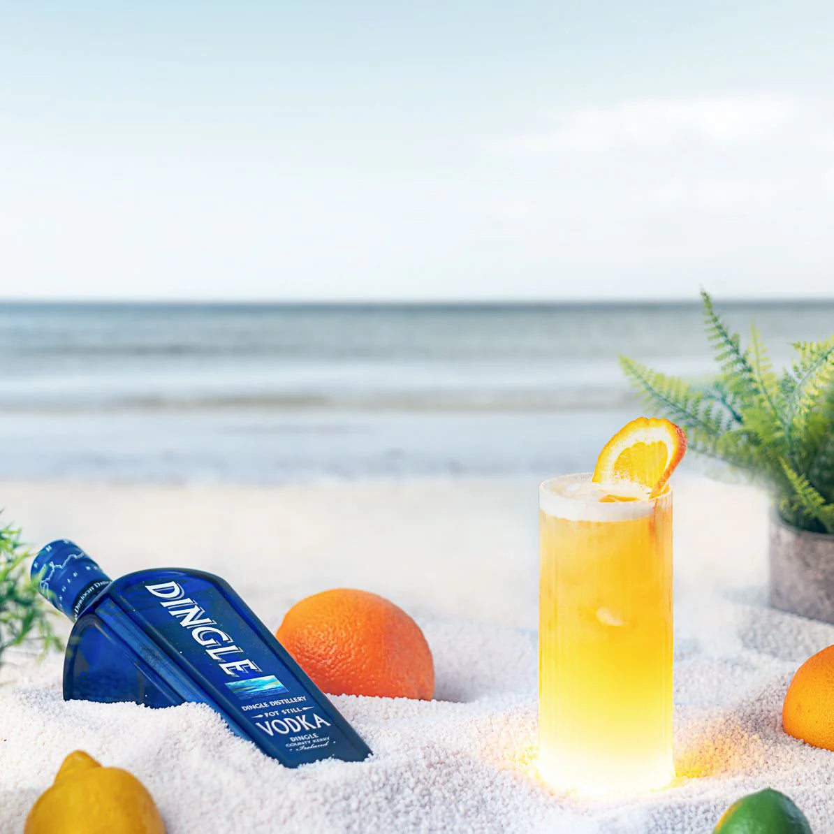 Load image into Gallery viewer, Dingle Vodka bottle with a cocktail and fruits on a beach setting