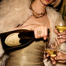 Load image into Gallery viewer, Person in a gold dress holding a bottle and two glasses of champagne.