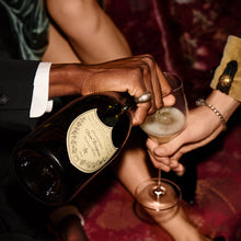 Load image into Gallery viewer, Person pouring champagne from a bottle into a glass held by another person.