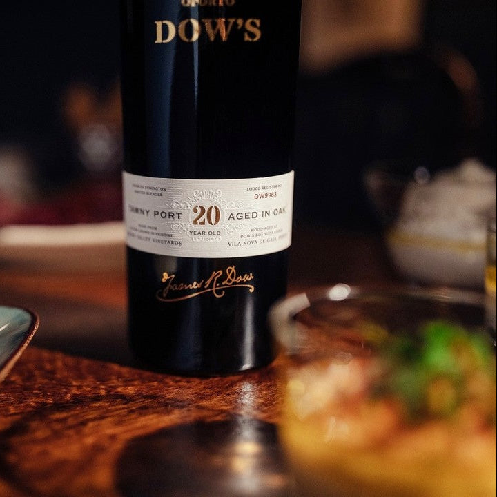 Bottle of Dow's Port wine on a table with food in the background