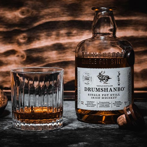 Load image into Gallery viewer, Drumshanbo Irish whiskey bottle and glass on a wooden surface