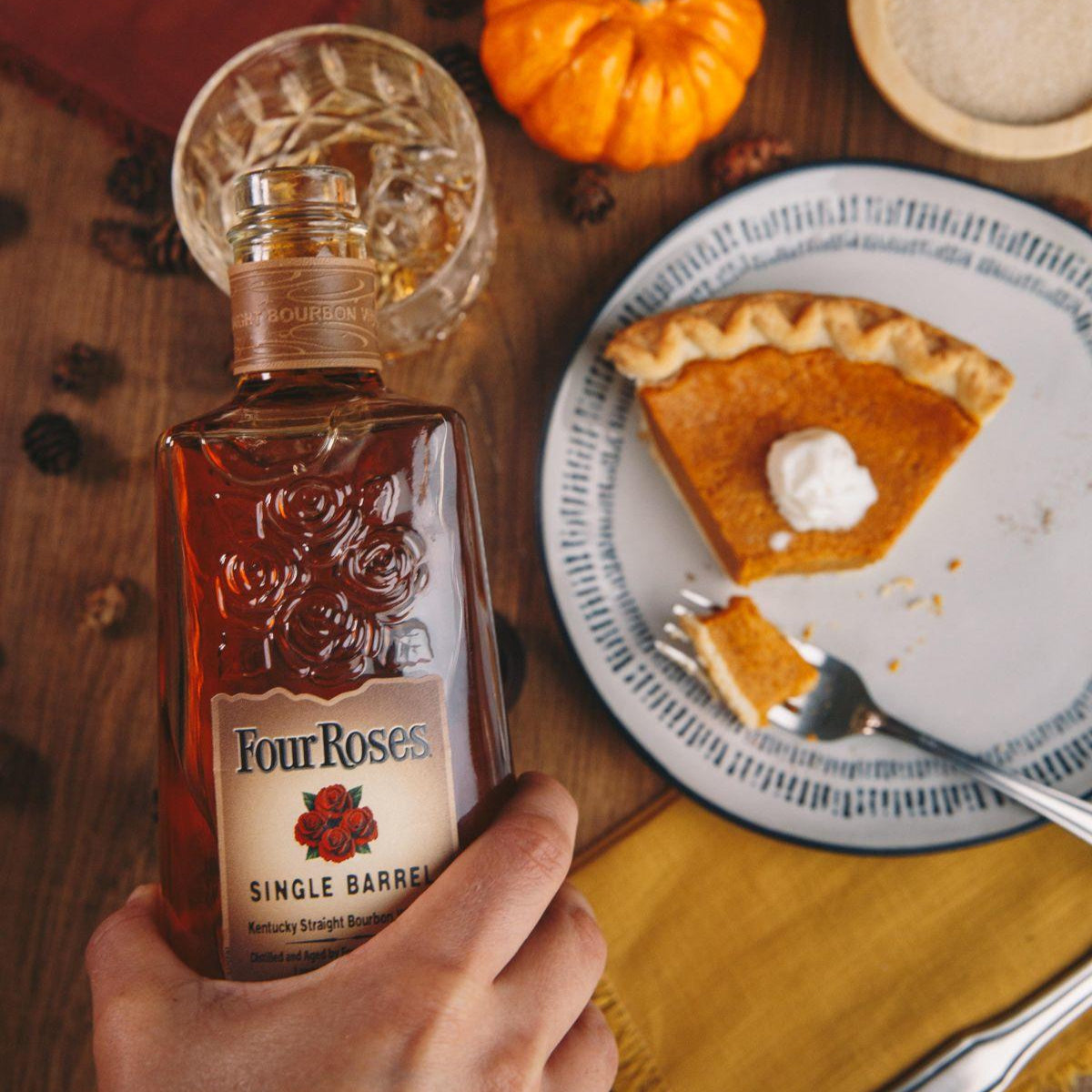 Load image into Gallery viewer, Four Roses whiskey bottle with a slice of pumpkin pie on a wooden table.