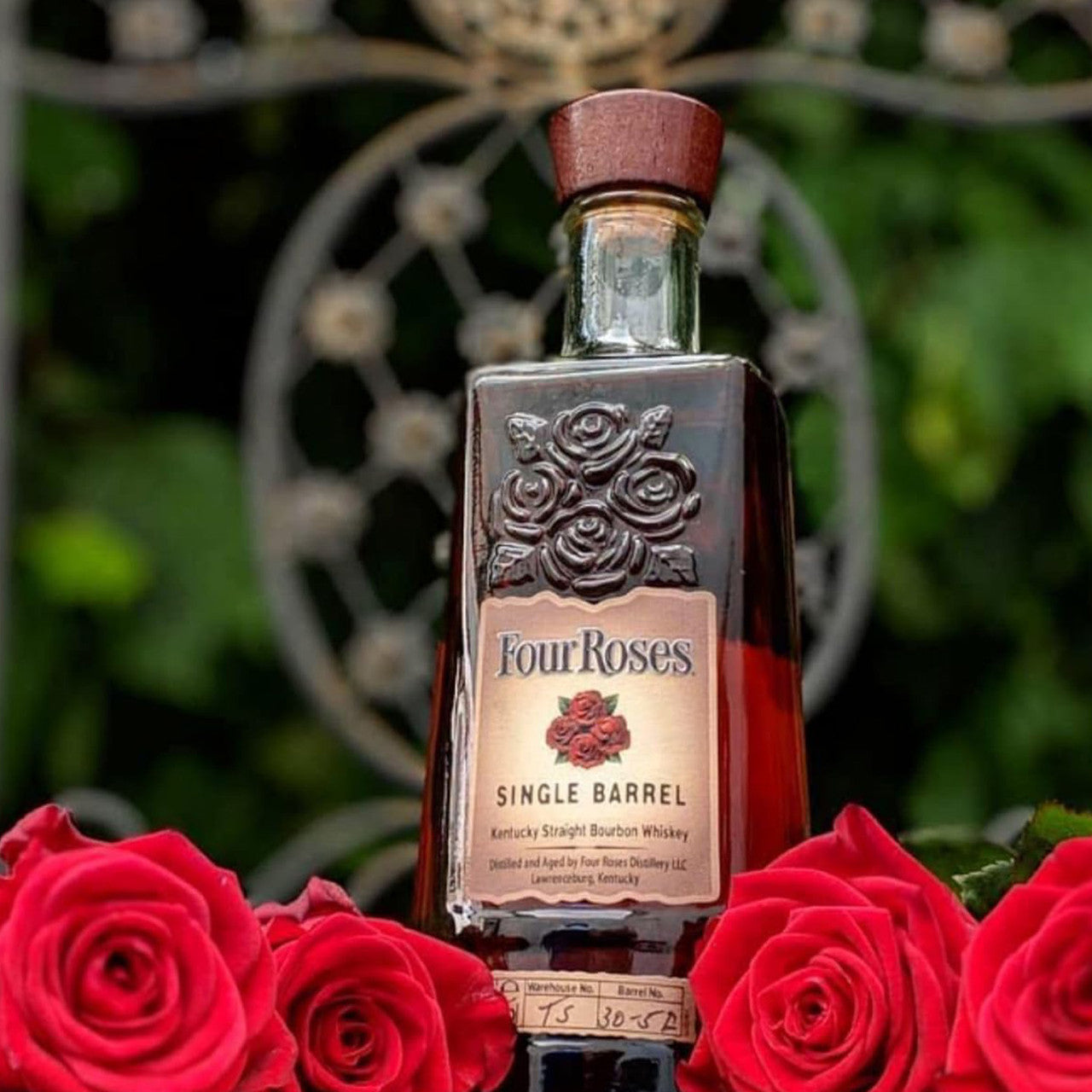 Load image into Gallery viewer, Four Roses Single Barrel bourbon bottle surrounded by red roses with a blurred natural background