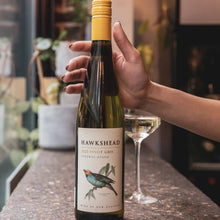 Load image into Gallery viewer, Hand holding a bottle of Hawkshead wine with a glass in the background