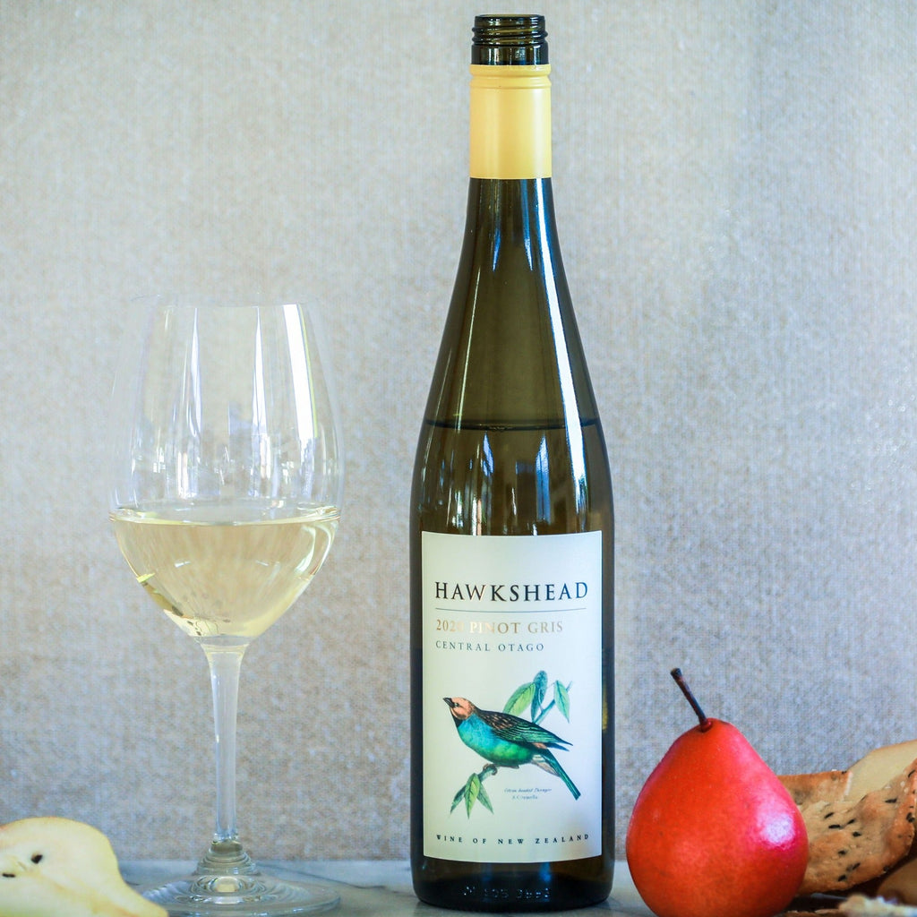 Bottle of Hawkshead wine with a glass of wine and fruit on a table.