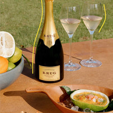 Load image into Gallery viewer, Bottle of Krug champagne with two glasses on a table outdoors.