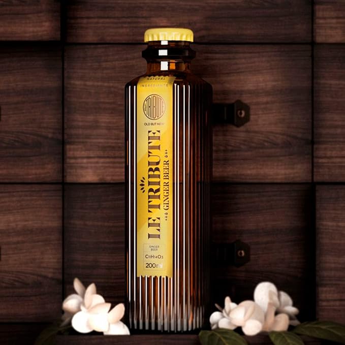 Load image into Gallery viewer, Bottle of 'Le Tribute' ginger beer on a wooden background with flowers.