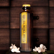 Load image into Gallery viewer, Bottle of &#39;Le Tribute&#39; ginger beer on a wooden background with flowers.