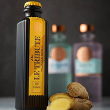 Load image into Gallery viewer, Bottle of Le Tribute Ginger Beer with ginger root on a dark background