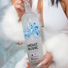 Load image into Gallery viewer, A woman holding a bottle of Mont Blanc Vodka with a blurred background