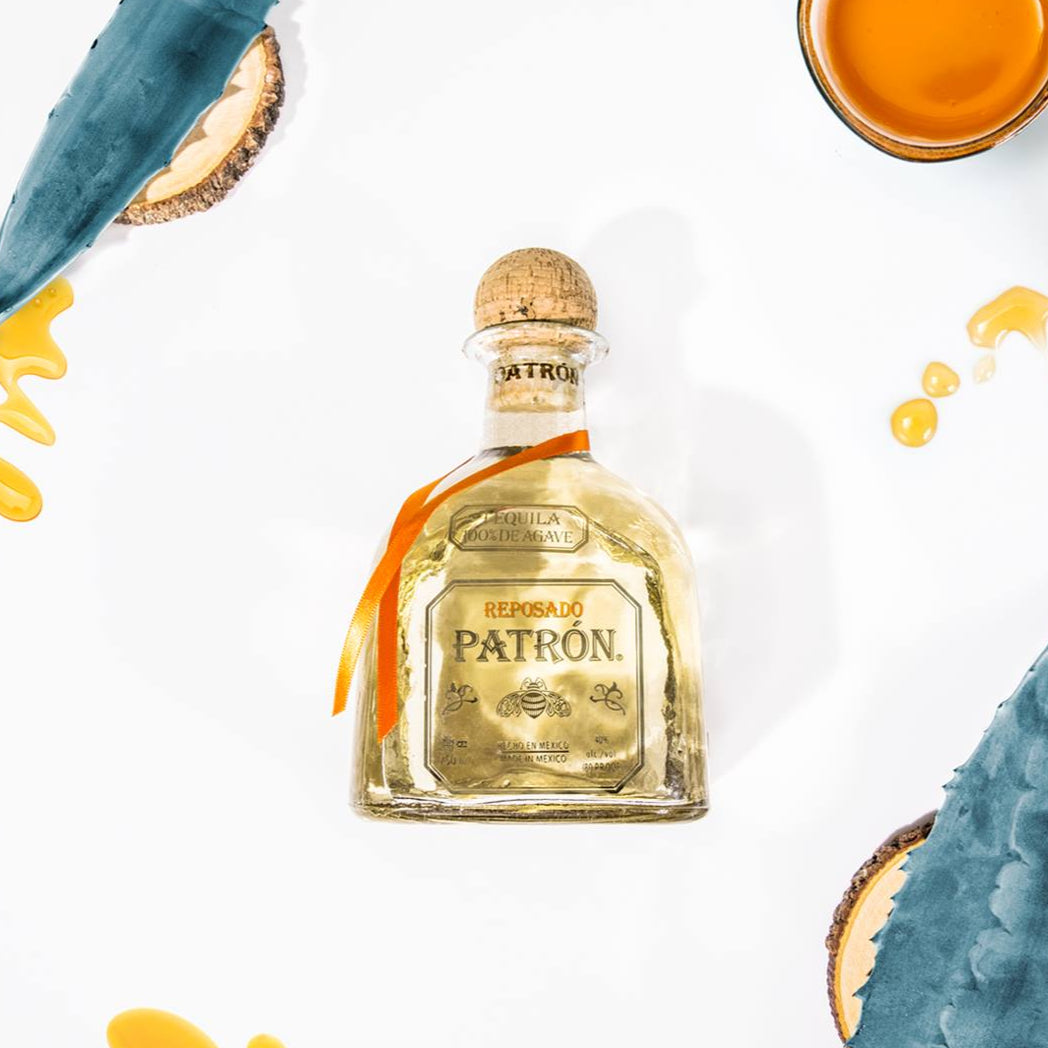 Load image into Gallery viewer, Patron tequila bottle with aloe vera leaves and honeycomb on a white background