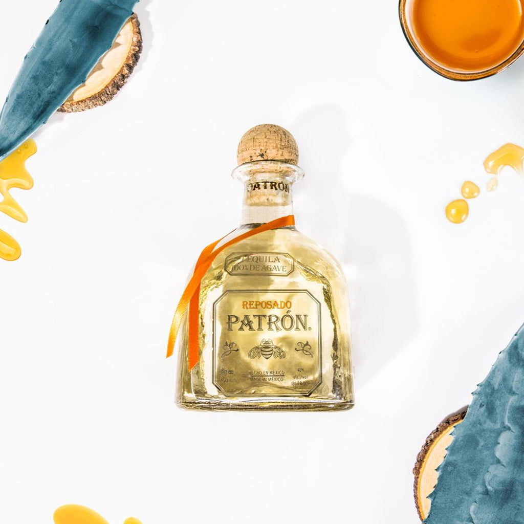 Patron tequila bottle with aloe vera leaves and honeycomb on a white background