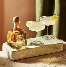 Load image into Gallery viewer, Patron tequila bottle with two cocktails garnished with lime on a stone surface.