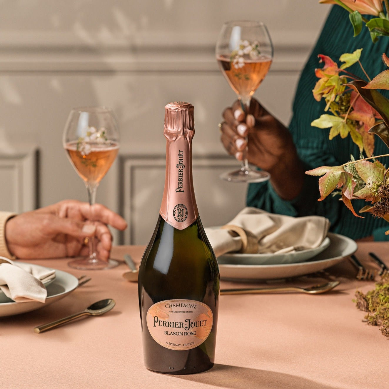 Load image into Gallery viewer, Champagne bottle on a table with people enjoying a meal in the background